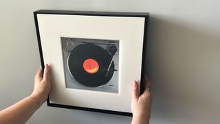 Hands holding Samsung Music Frame against white wall