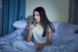 A woman drinks water before going to sleep