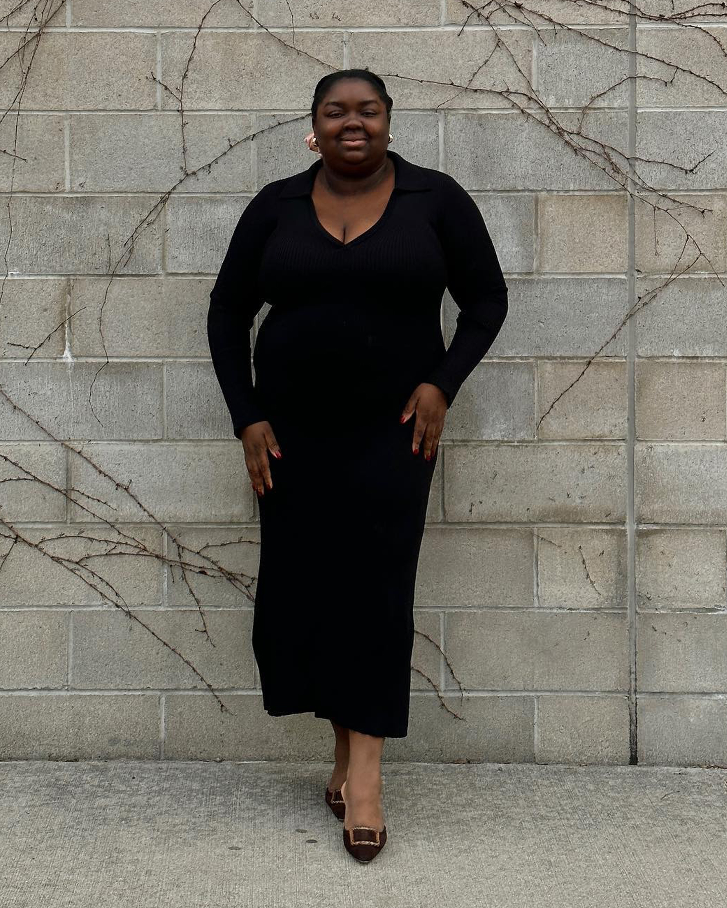 style influencer Abisole Omole poses in a V-neck black long-sleeve maxi dress with Manolo Blahnik kitten heels