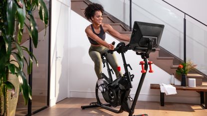 Attractive young woman using the Bowflex VeloCore exercise bike in a living room