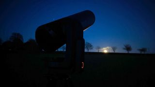Telescope in front of rising full moon