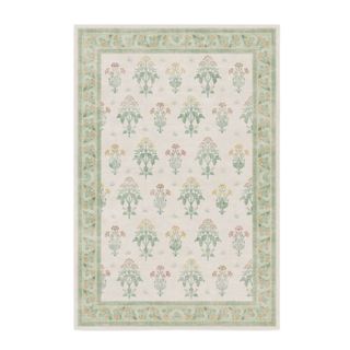 A green and beige rectangular rug with bouquet illustrations of yellow and pink flowers on it