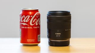 A 330ml Coca Cola can on the left compared to the Canon RF 28-70mm F2.8 IS STM lens on the right to show they have a similar form factor