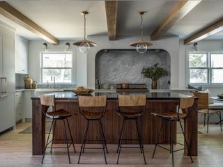 a rustic kitchen with a wooden island and beams across the ceiling