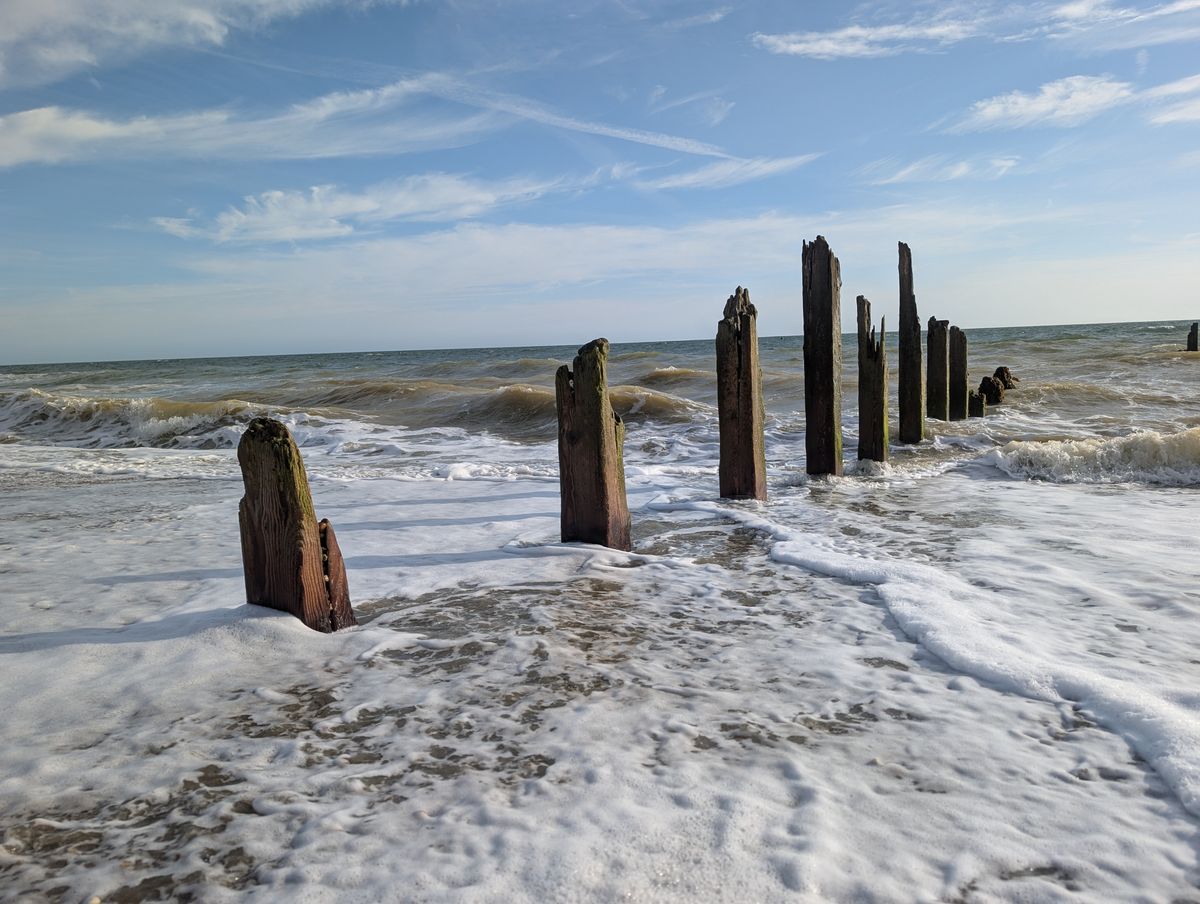 A damaged groyne on a UK beach, the high tide is smashing into it