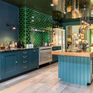 kitchen area with green tiles and wooden floor and blue counter with wooden countertop