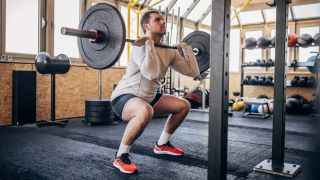 Man performing front squat with a barbell in a gym