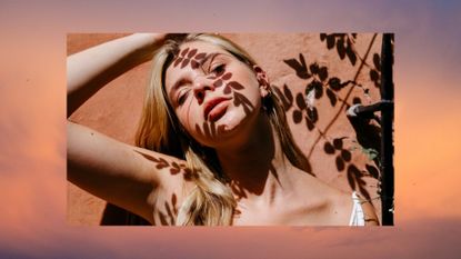 Young woman against wall with leaves shadow on face during sunny day - stock photo in a MIL template