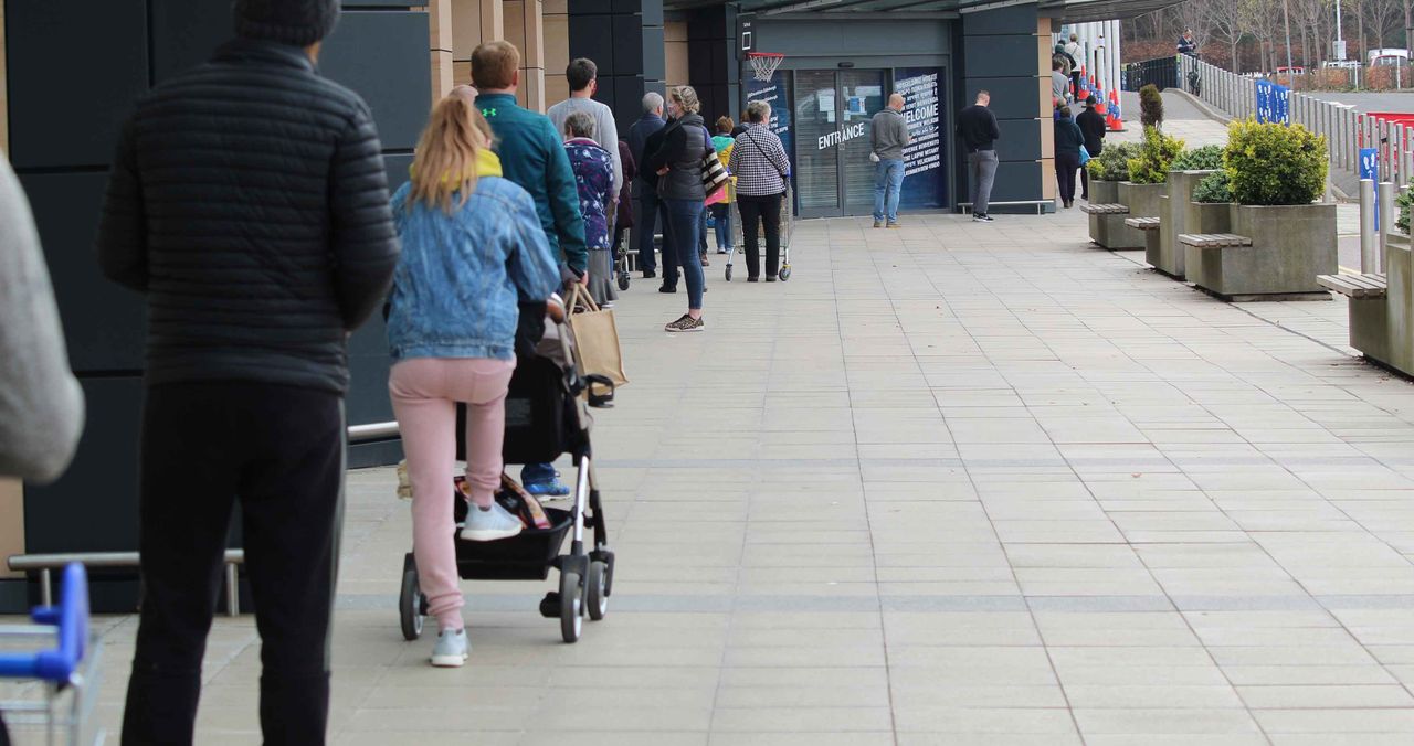 Photo of socially distanced shoppers waiting to enter store.