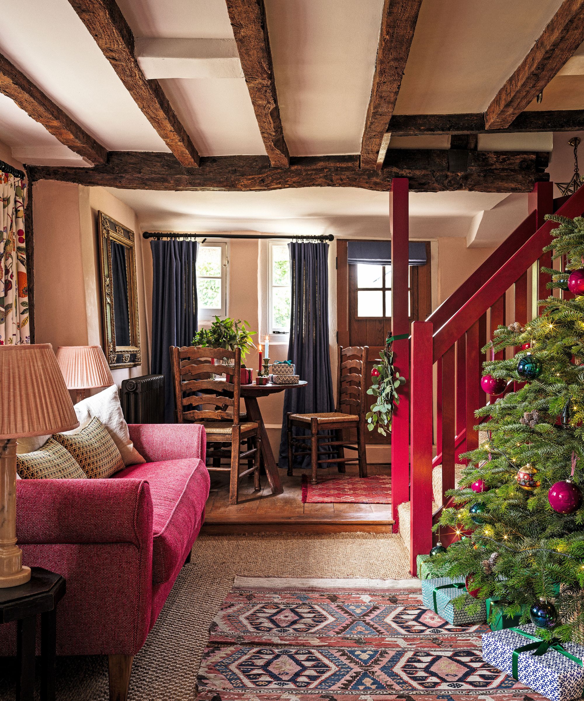 Entryway decorated for christmas with a red painted staircase and a tree next to the stairs