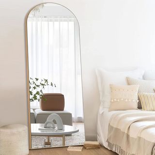 Gold arched full length mirror in a bedroom