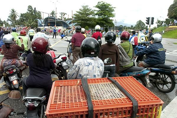 The peloton turn onto the road to Genting Highlands as locals on scooters catch a glimpse of the tour.