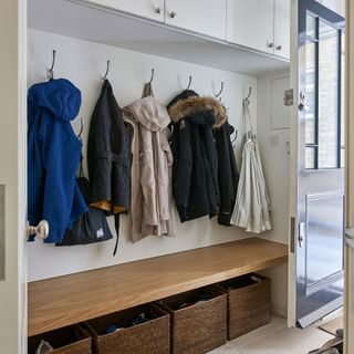 boot room with white cabinets and hanging jackets