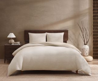 Egyptian Cotton sheets on a bed against a beige wall.