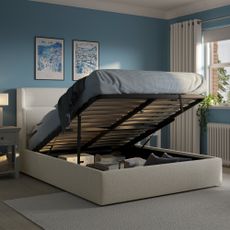 An ottoman bed in a blue bedroom with the mattress lifted