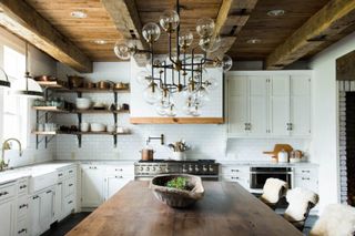 Large farmhouse kitchen with rustic wooden shelves and glass globes chandelier