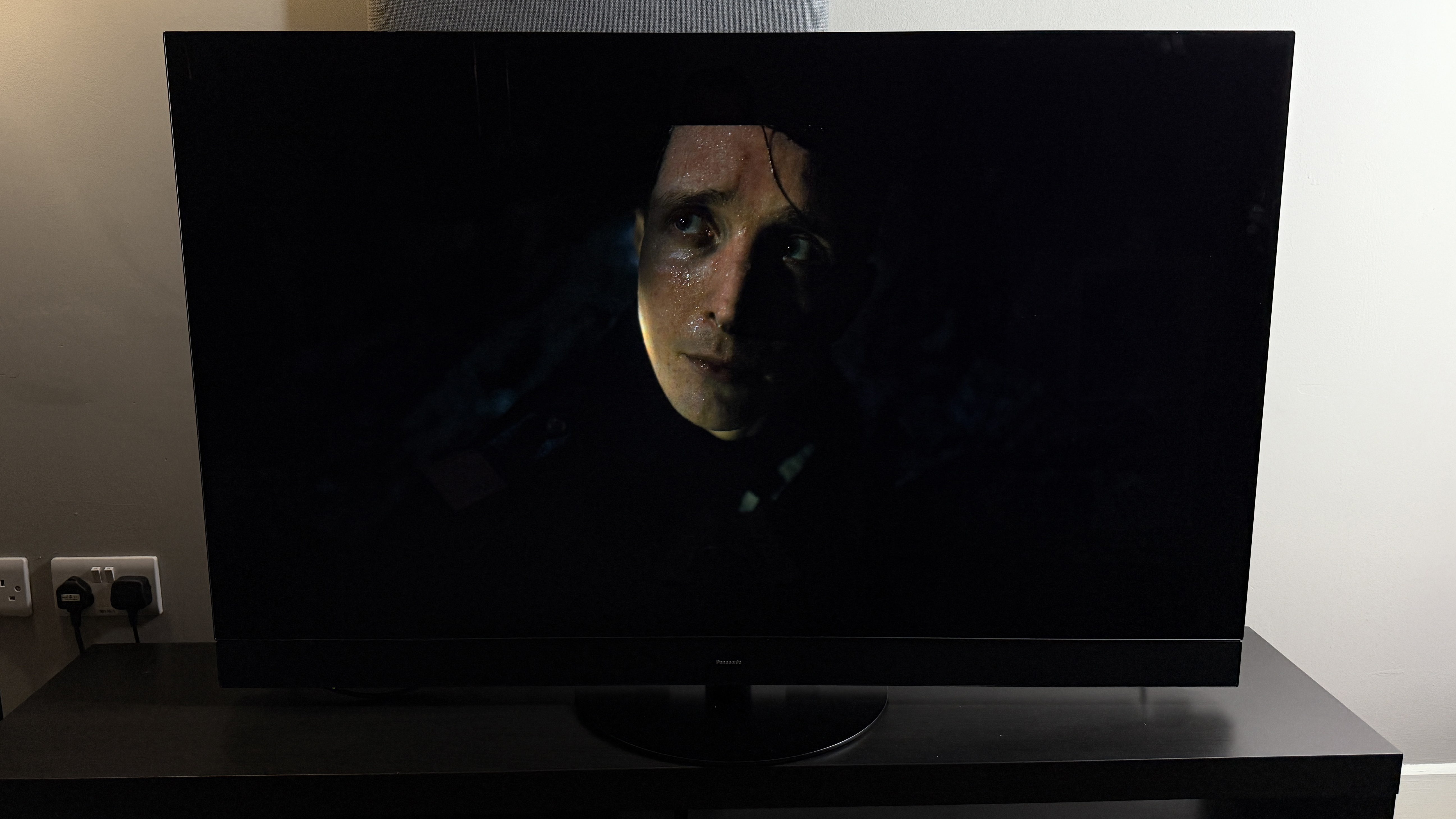 Photo of The Last Voyage of the Demeter on a TV, showing a man standing over a man's scared face in the darkness