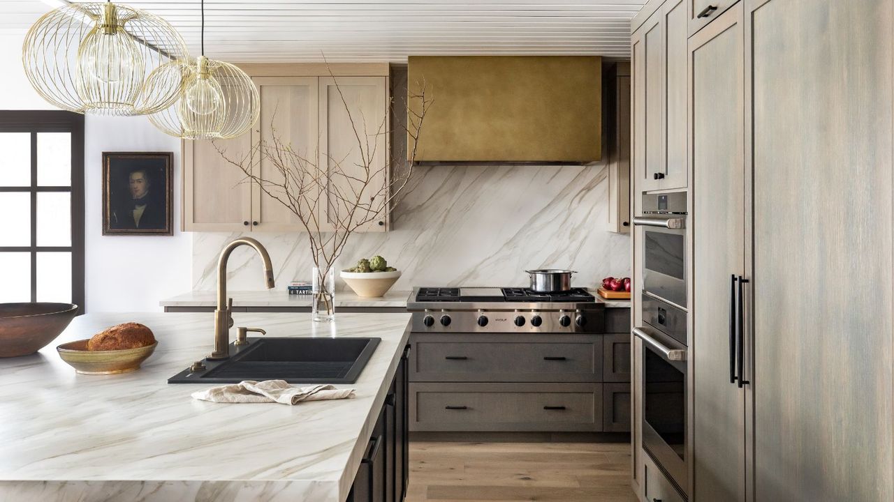 Pale wooden kitchen with marble island and gold range hood