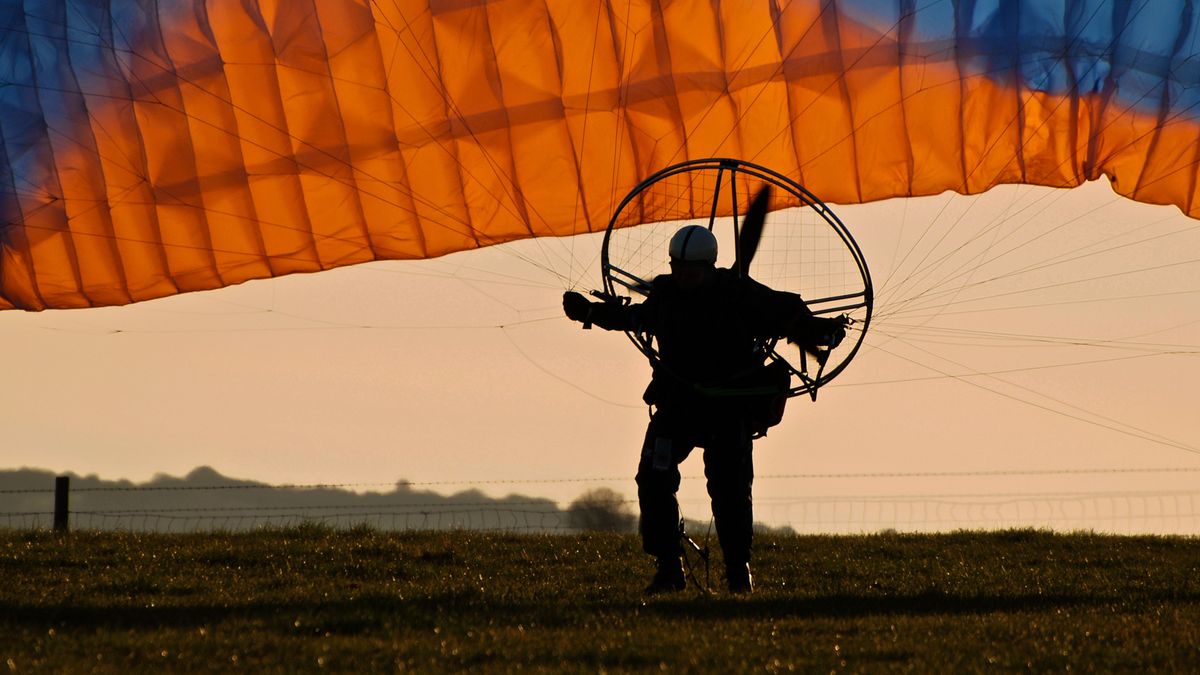 Paramotorist taking off at sunset