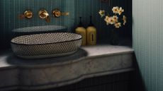 Teal guest bathroom featuring a decorative ceramic sink basin, marble countertop, magnolia flowers, and luxury hand soaps.