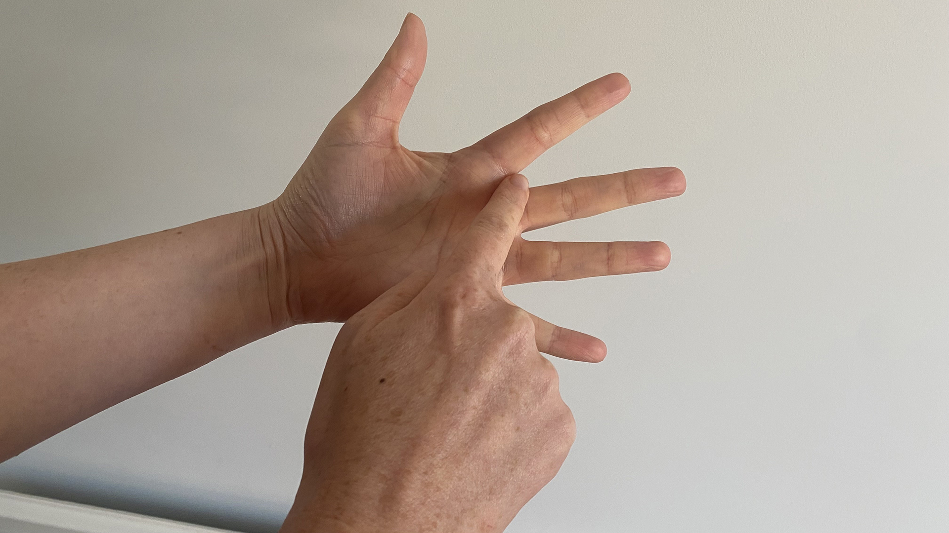 A close up of two hands using the finger breathing relaxation for technique, with the trace finger resting between the index and middle finger