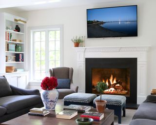 White living room with TV mounted on wall, coffee table, pouf, white shelving