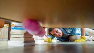 A woman cleaning under the bed