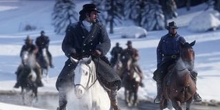 Cowboys ride through the snow in Red Dead Redemption 2.