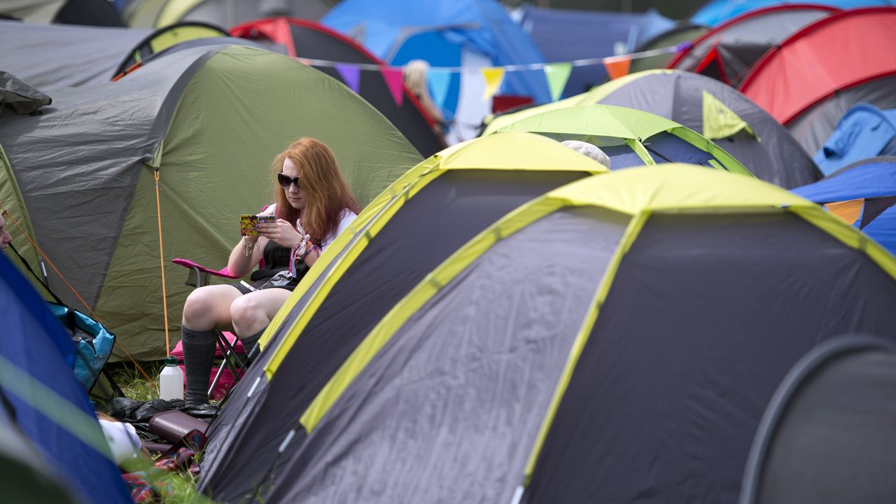 A reveller uses a smartphone to see the acts that will perform at attend the Glastonbury Festival 