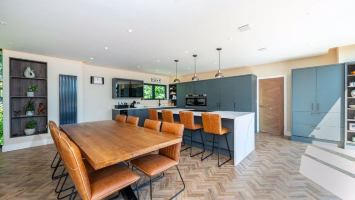 A kitchen with wooden panelled floor and kitchen island with pale blue cupboards
