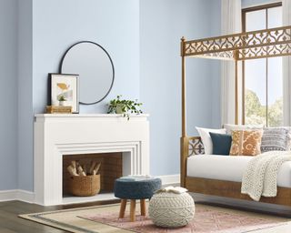 bedroom with light blue walls, fireplace and four poster bed