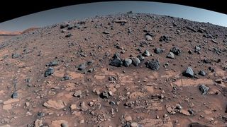 a panoramic view of the surface of Mars from the top of a ridge, littered with rocks and hills