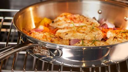 All-Clad frying pan in an oven, with baked shrimp inside. 