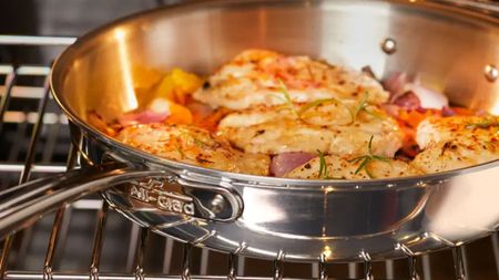 All-Clad frying pan in an oven, with baked shrimp inside. 