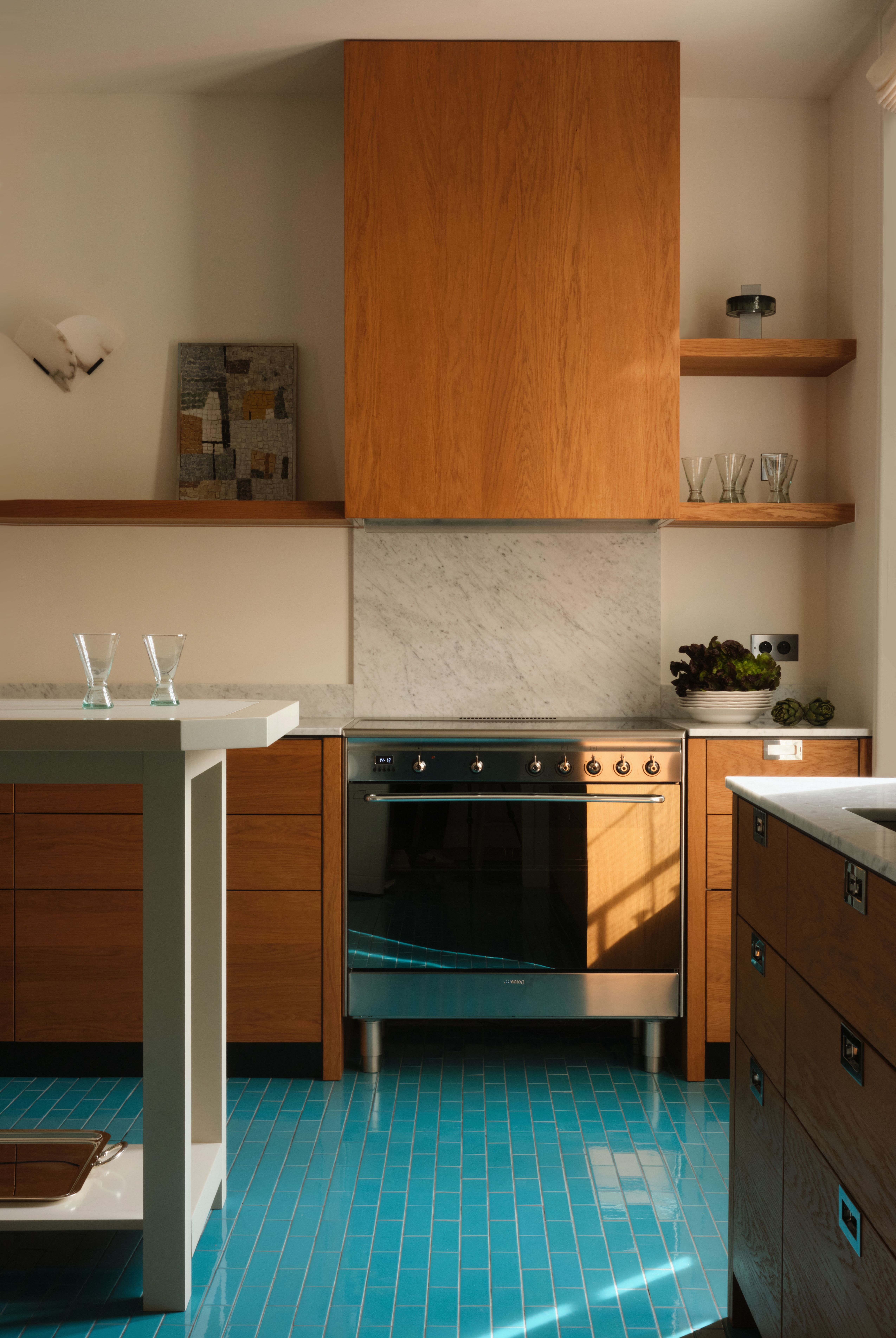 A colorful kitchen pairing wood, marble, and sleek chrome with a glazed ceramic floor of blue tiles.