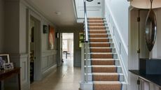 light blue painted large entryway hall with painted stairs and a jute runner with blue edging