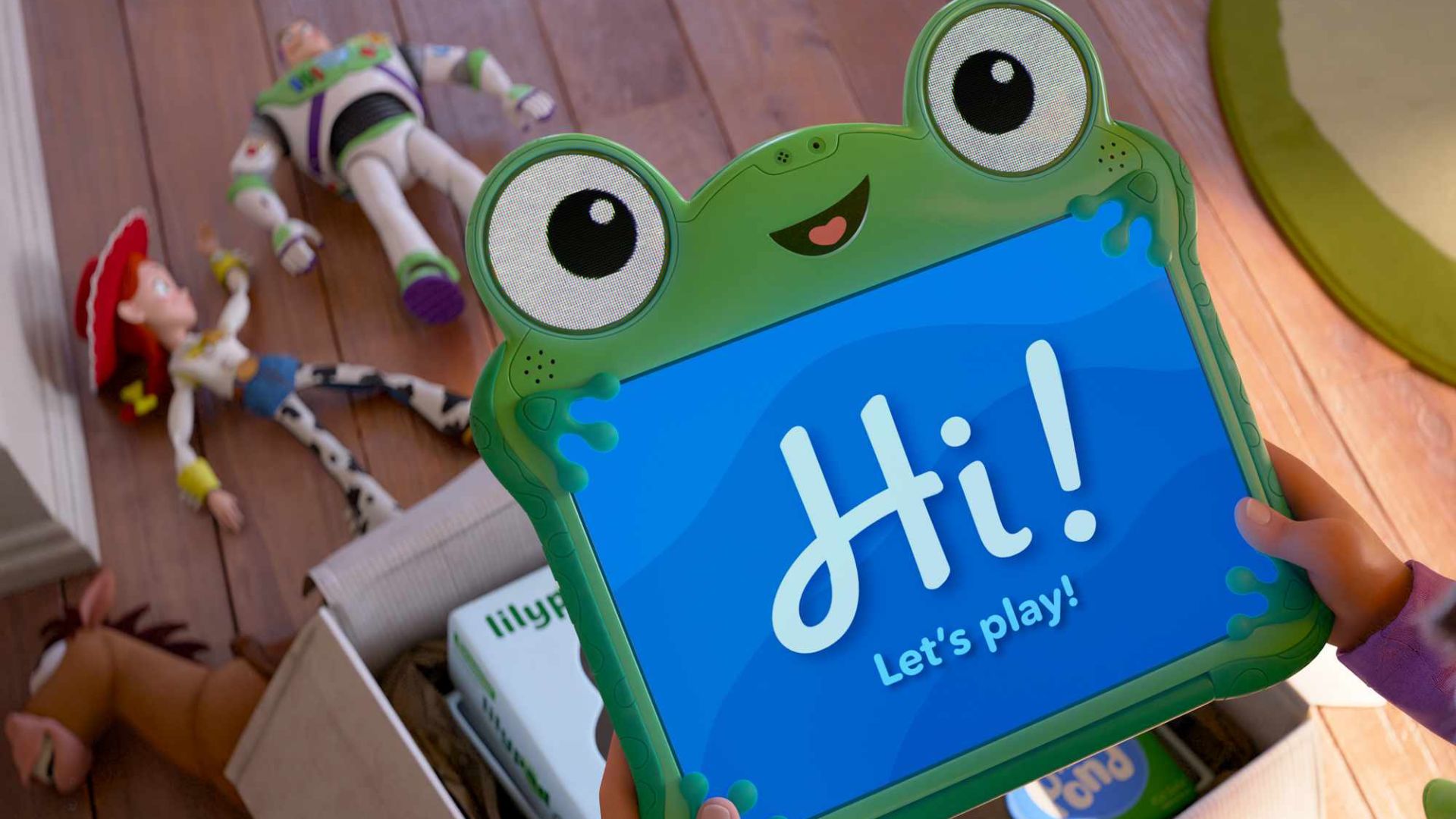 A child holds a frog-shaped tablet that reads &amp;quot;Hi! Let&#039;s Play!&amp;quot;