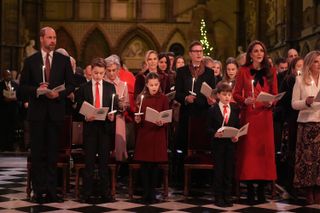 Kate Middleton holding a candle and singing next to Prince Louis, Prince George, Princess Charlotte and Prince William in church