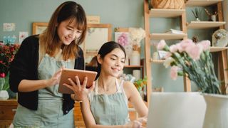 Woman and young girl smiling and looking at laptop
