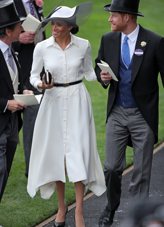 Britain's Prince Harry, Duke of Sussex, (R) and his wife Britain's Meghan, Duchess of Sussex (C) talk with the Queen's Bloodstock and Racing Advisor, John Warren on day one of the Royal Ascot horse racing meet, in Ascot, west of London, on June 19, 2018