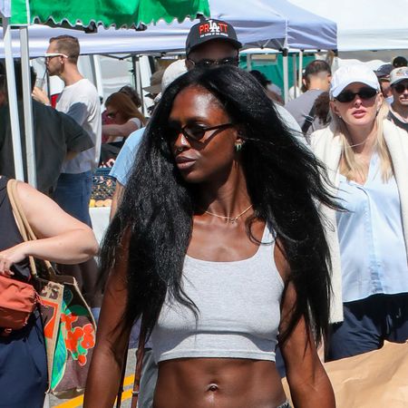 Jodie Turner-Smith wearing a gray tank top, gray denim drawstring jeans, and black Vibram fivefinger shoes