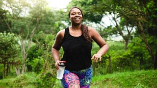 A woman trail running with a bottle of water