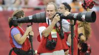 Photographer Heinz Kluetmeier stands on the sidelines of an NFL game with a Nikon camera and telephoto lens