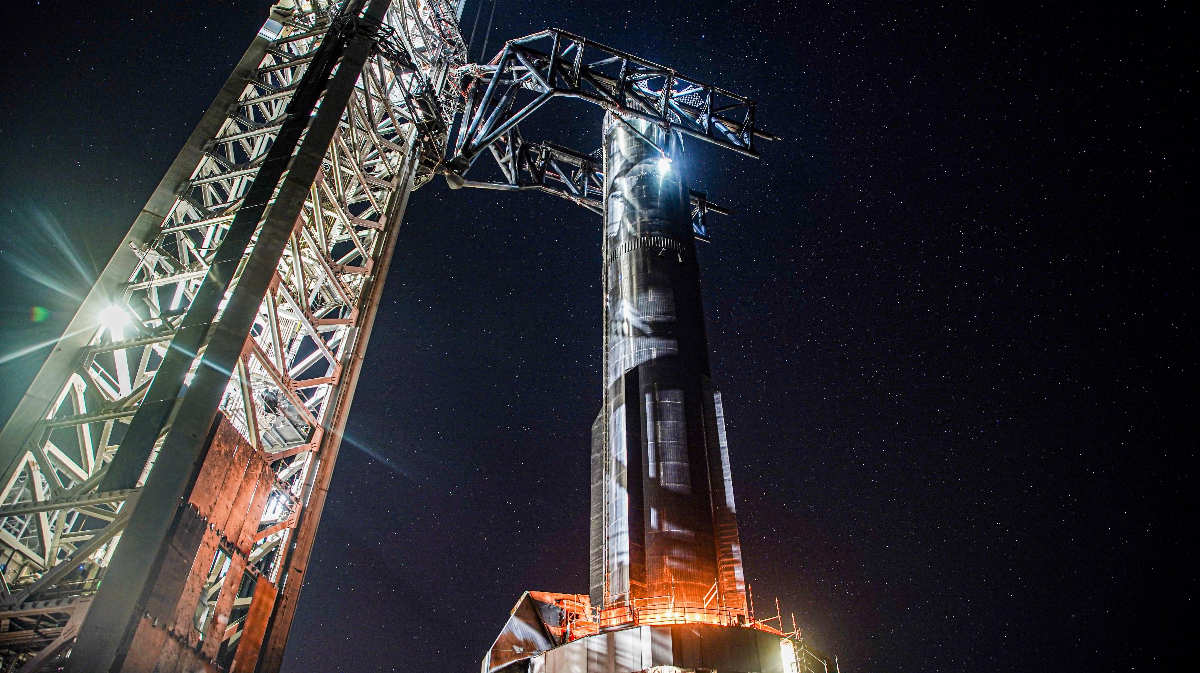 el propulsor superpesado plateado Spacex se baja a la plataforma de lanzamiento por la noche