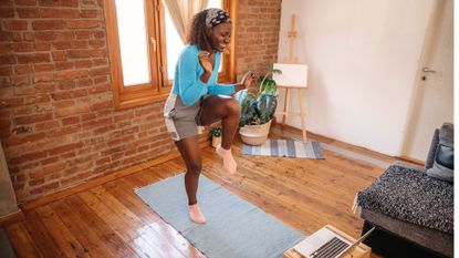 woman does a walking workout at home in front of her laptop
