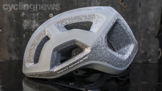 Side view of a light grey helmet with exposed grey polystyrene padding