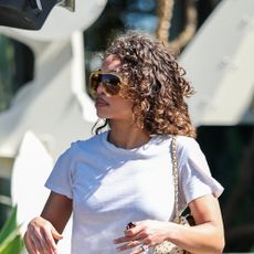 Lori Harvey wearing a white cropped tee, dark wash jeans, and black flip-flops