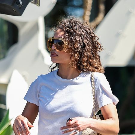 Lori Harvey wearing a white cropped tee, dark wash jeans, and black flip-flops