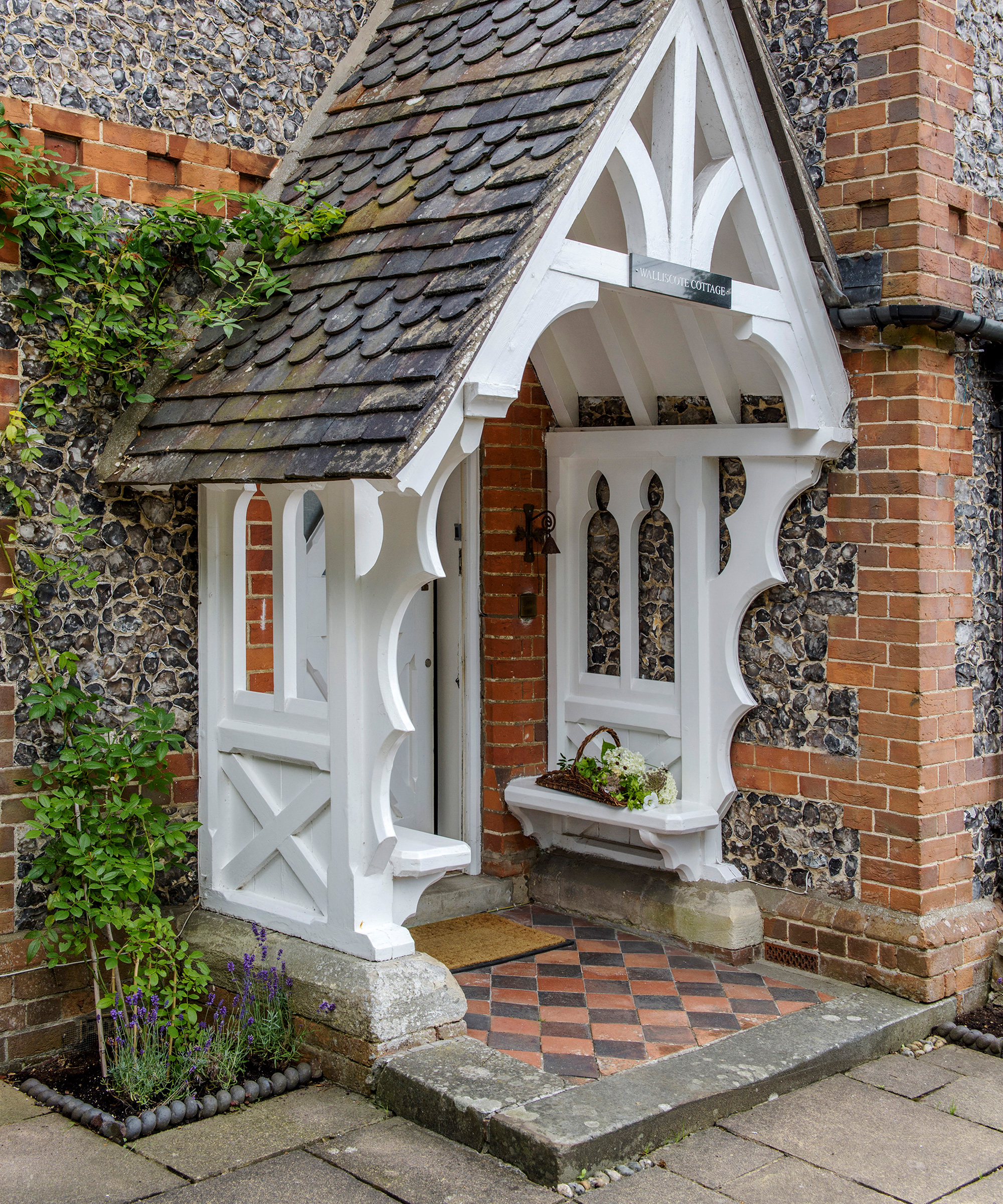 An example of how to decorate a front porch showing a period home with a decorative white porch with a pitched roof and original black and red tiles