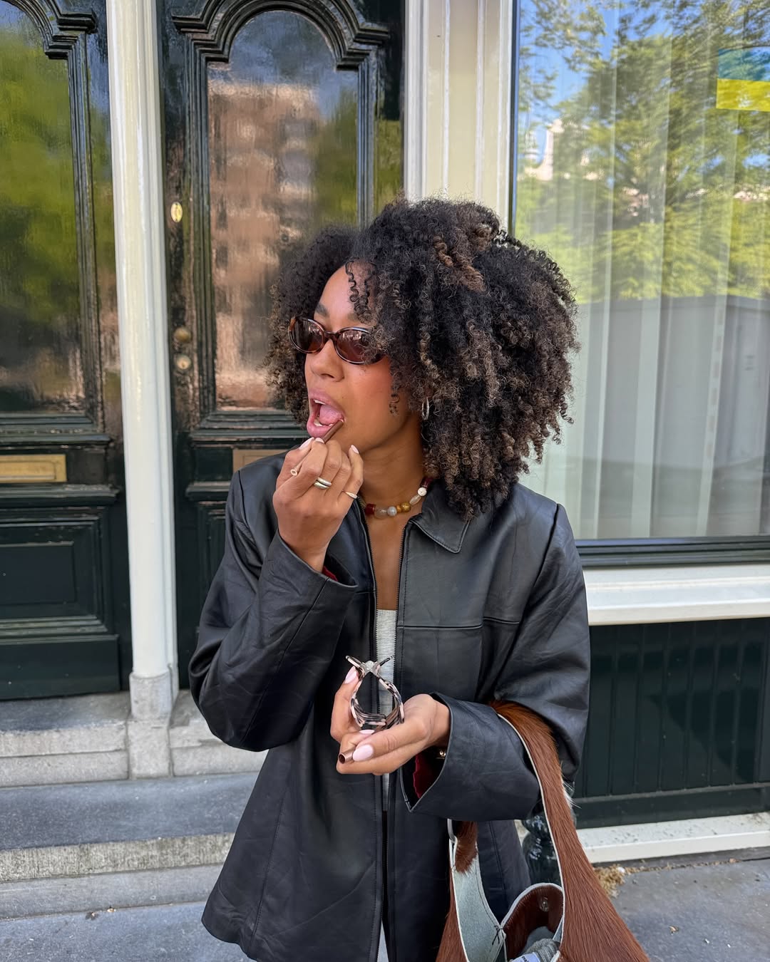 Amaka Hamelijnck shows off her healthy, bouncy curls while reapplying her lip liner in Amsterdam, The Netherlands.